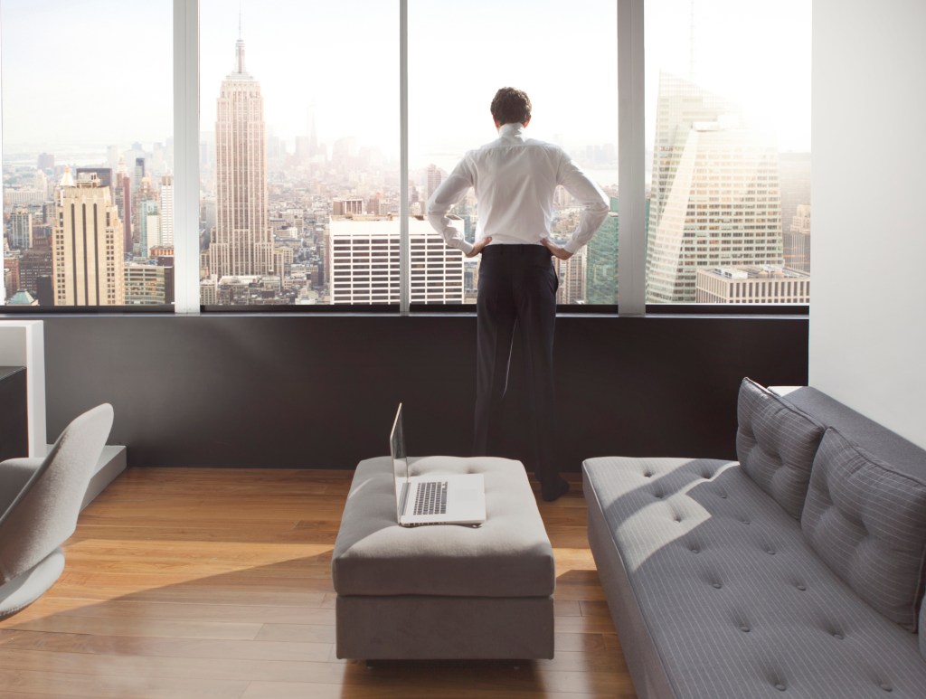 Young man looking out at city skyline.