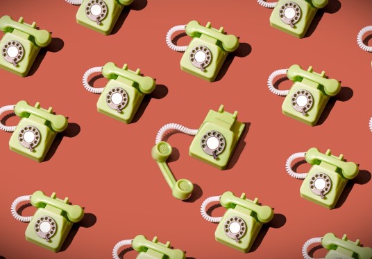 High angle view of some vintage green rotary telephones arranged on a brown background, showcasing retro communication technology with a nostalgic and artistic flair